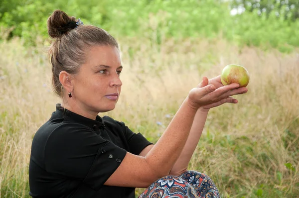 Mulher de meia-idade com uma maçã na mão — Fotografia de Stock
