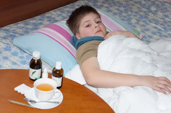 病気の少年はベッドで横になっています。テーブルの上の薬 — ストック写真
