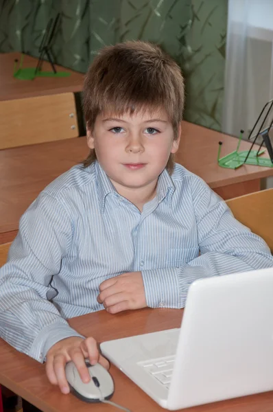 Školák u stolu s přenosným počítačem v třídě školy — Stock fotografie