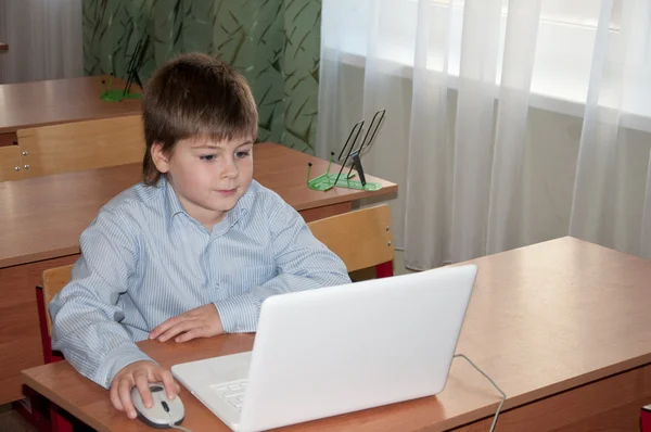 Skolpojke vid sitt skrivbord med en laptop i klassen i skolan — Stockfoto