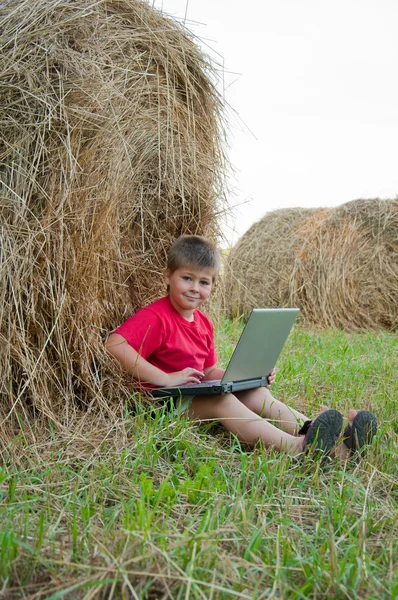 Un chico con un portátil en el campo —  Fotos de Stock