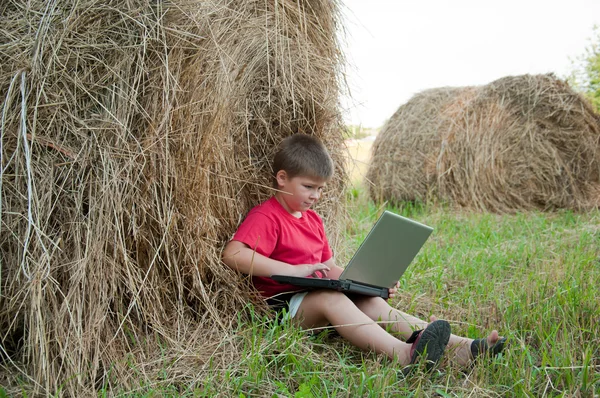 Ένα αγόρι με ένα φορητό υπολογιστή στο πεδίο — Φωτογραφία Αρχείου