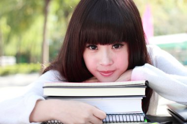 gülümseyen bir Asya öğrenci okuyor.