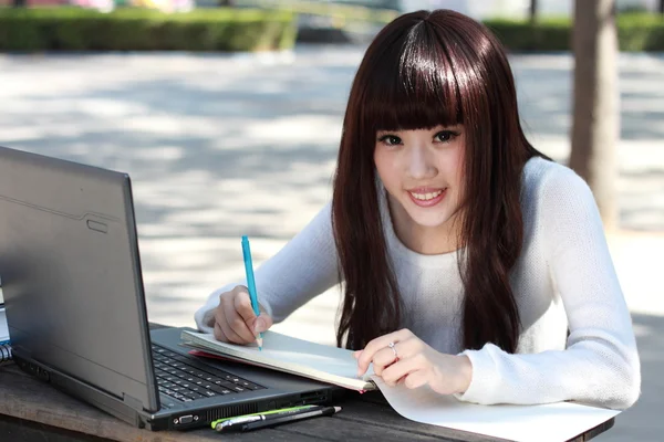 Una estudiante asiática sonriente está estudiando . Imágenes de stock libres de derechos