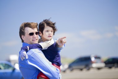 Father holding disabled son on the beach clipart