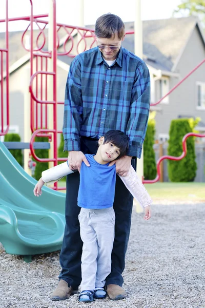 Padre ayudando a hijo discapacitado en el patio — Foto de Stock