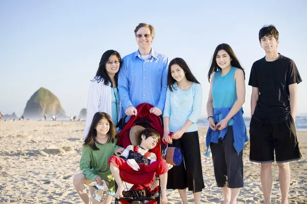 Amplia familia de siete de pie en la playa junto al océano —  Fotos de Stock
