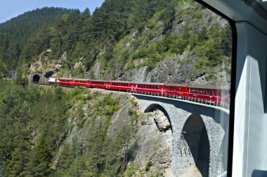 Glacier Express driving over a viaduct into a tunnel clipart
