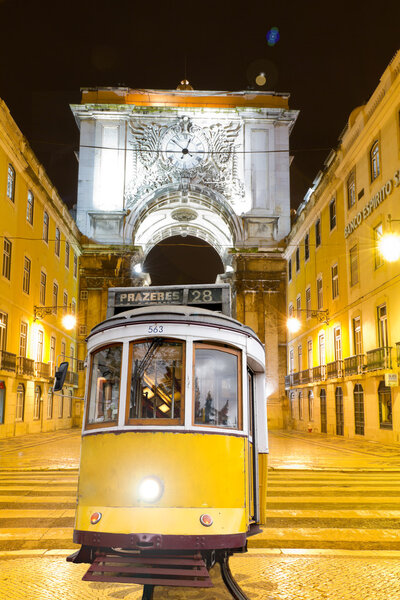 Lisbon: old yellow tram with triumphal arch, Portugal