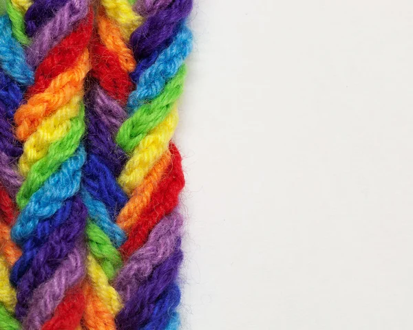 Fios de lã de cores diferentes, tecida em uma trança, sobre um fundo branco w — Fotografia de Stock