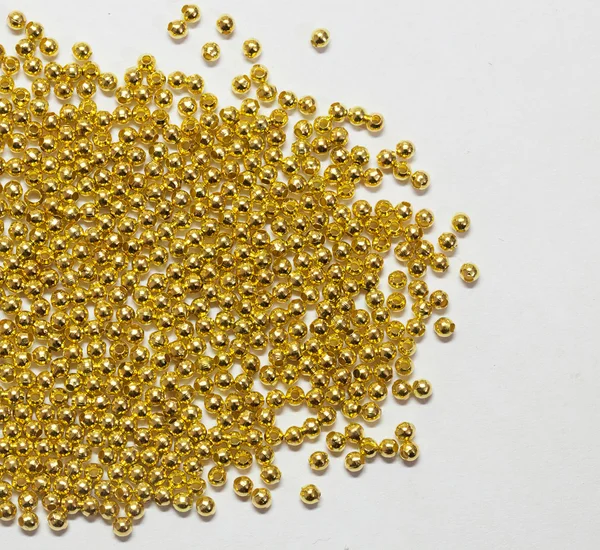 Gold jewelry beads from spilling on white background