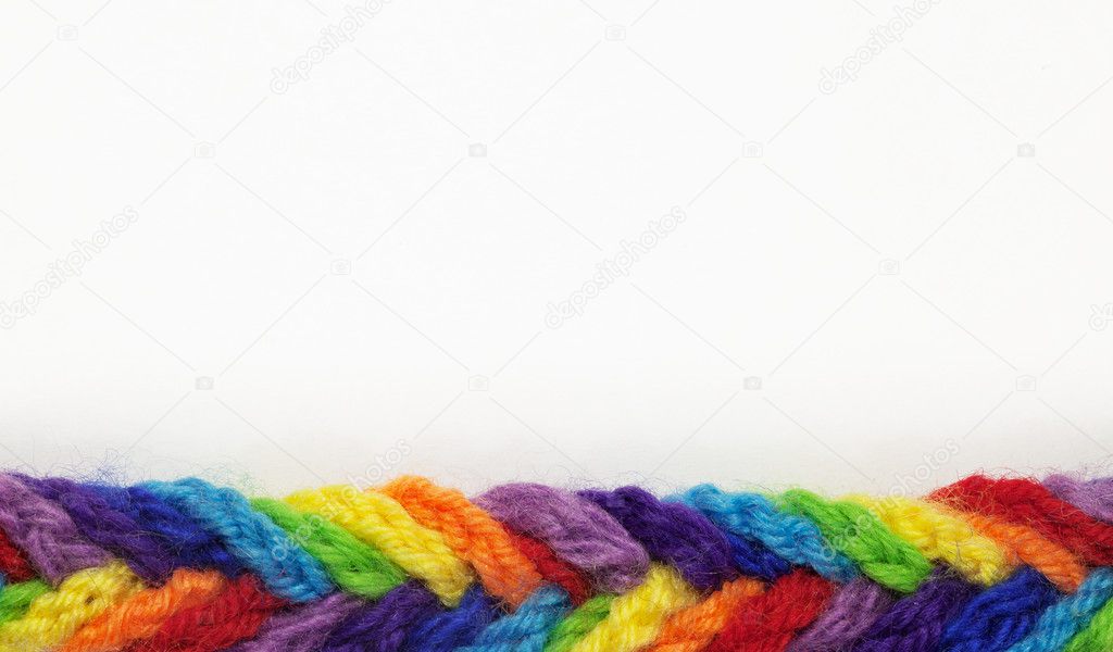 Wool yarns of different colors, woven into a braid, on a white background w
