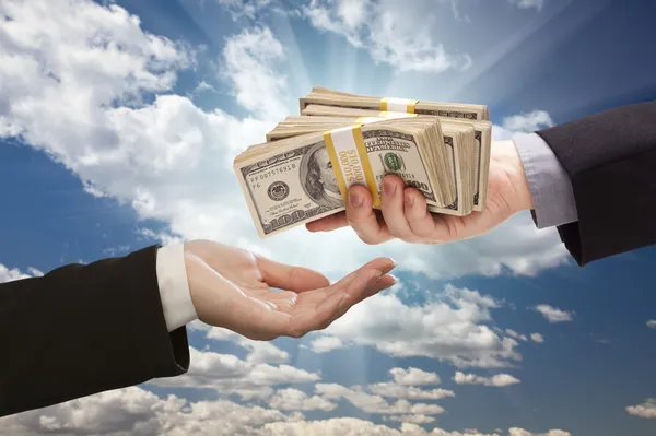 Entregando dinheiro com nuvens dramáticas e céu — Fotografia de Stock