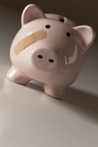 Piggy bank met pleister op gezicht — Stockfoto