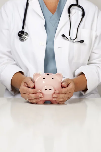 Doutor com as mãos atenciosas em um Piggy Bank — Fotografia de Stock