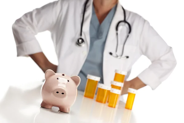 Доктор, стоящий за бутылками с лекарствами и копилкой свинины — стоковое фото