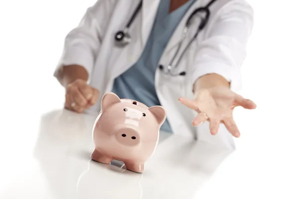 Anspruchsvoller Arzt streckt Hand hinter Sparschwein aus — Stockfoto
