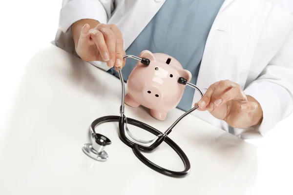 Doctor Holds Stethoscope to Ears of Pink Piggy Bank — Stock Photo, Image