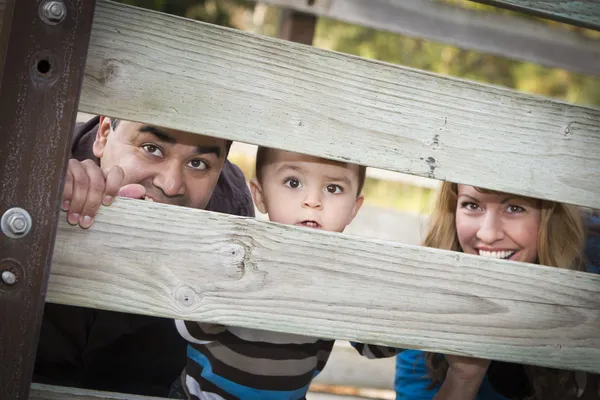 Šťastné mladé smíšené rasy etnické rodina dívat se skrz plot — Stock fotografie