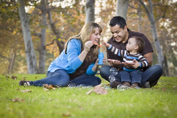 Familia étnica de raza mixta feliz jugando con burbujas en el parque — Foto de Stock