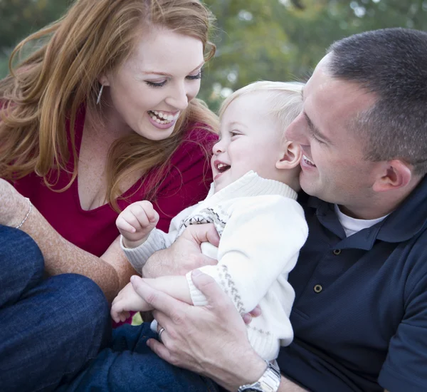 Aantrekkelijke jonge ouders lachen met kind jongen in park — Stockfoto