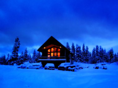 Winter Cabin at night with glowing warm windows clipart