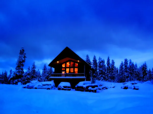 Cabine de Inverno à noite com janelas quentes brilhantes — Fotografia de Stock
