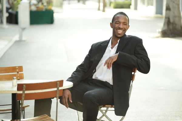 Бизнесмен сидит на улице и улыбается — стоковое фото