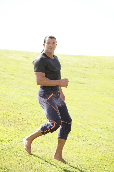 Athletic man running in the field — Stock Photo, Image