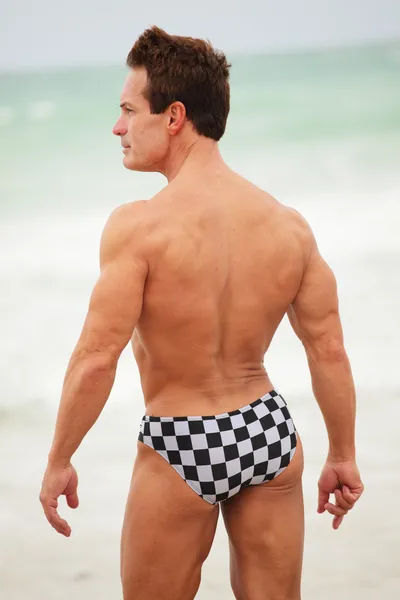 Achteraanzicht van een bodybuilder op het strand — Stockfoto