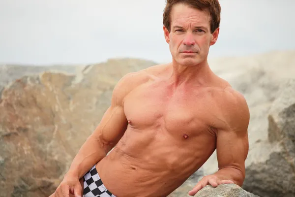 Bodybuilder poserar på klipporna — Stockfoto