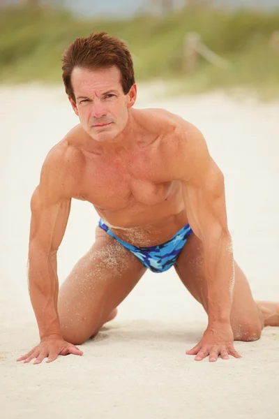 Bodybuilder posiert im Sand — Stockfoto