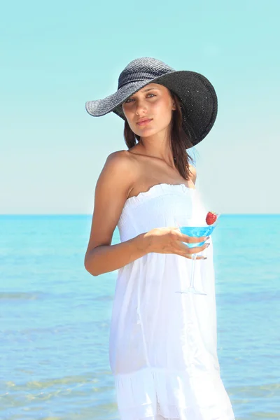 Молодая женщина на пляже с коктейлем — стоковое фото