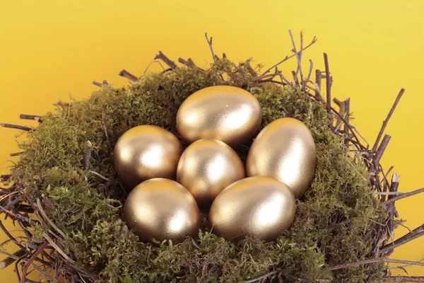 Złote jaja w gnieździe ptak nad żółty — Zdjęcie stockowe