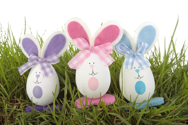 Цветные пасхальные яйца кроликов на траве над белым — стоковое фото