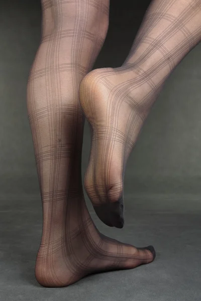 Kobieta nogi i stopy rajstopy na szary — Zdjęcie stockowe