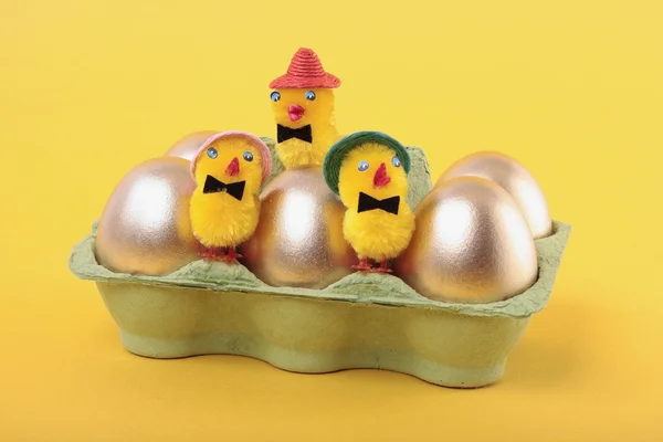 Золоті великодні яйця і пташенята в коробці над жовтим — стокове фото