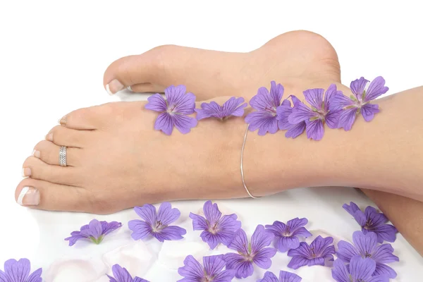 Kvinnliga fötter med blommor isolerade över vit bakgrund — Stockfoto