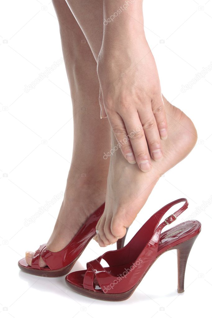 Woman legs wearing high heels massaging aching feet over white b