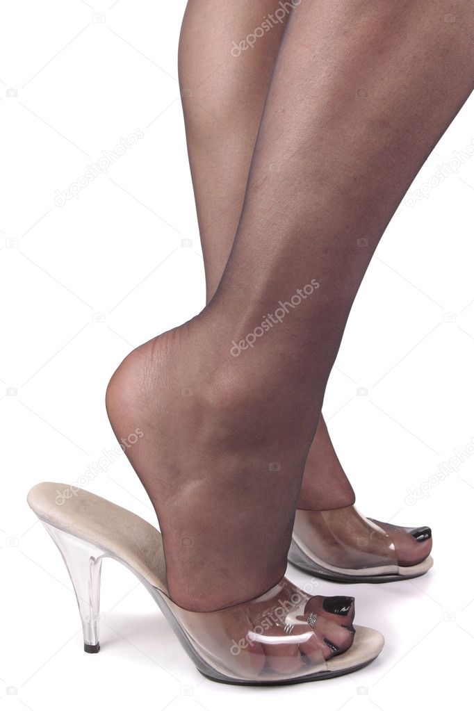 Femal legs wearing tights and clear high heels over white backgr