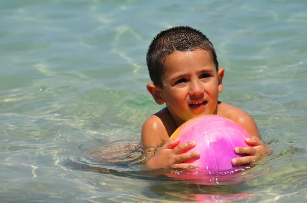 Мальчик с мячом в море — стоковое фото