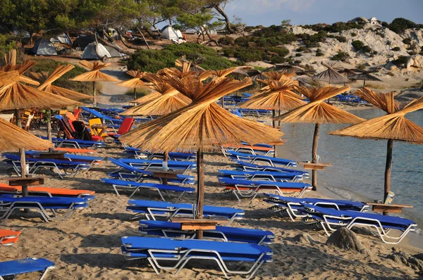 Playas griegas de arena blanca y piedra, con cafés y sombrillas de playa de pa — Foto de Stock