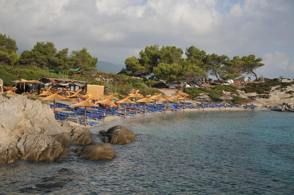 Playas griegas de arena blanca y piedra, con cafés y sombrillas de playa de pa — Foto de Stock