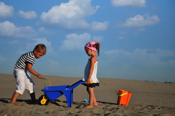 Flickor och en pojke som leker på stranden sand — Stockfoto