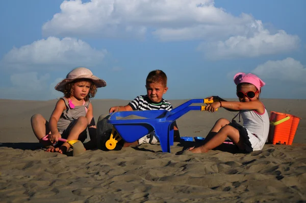 Dos chicas y un chico jugando en la arena de la playa —  Fotos de Stock