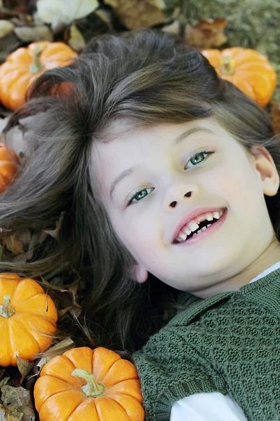 Criança deitada em folhas de outono — Fotografia de Stock