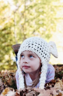 Child Lying in Autumn Leaves clipart