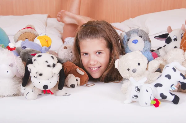 Chica acostada en la cama con juguetes —  Fotos de Stock