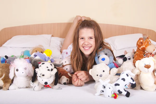 Menina na cama com brinquedos — Fotografia de Stock