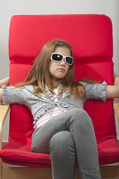 Pretty young teenage girl resting in the red chair with sunglasses on her h — Stock Photo, Image
